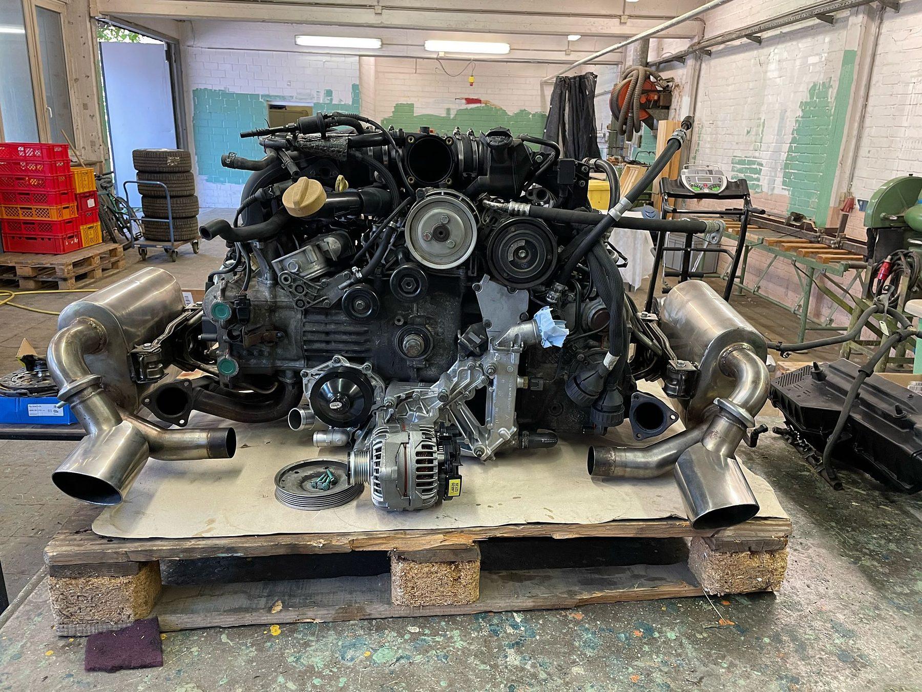Ausgebauter Boxermotor mit Abgasanlage auf einer Palette in der Werkstatt